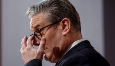 Keir Starmer addressing media on Iran policy with flags and microphones in the background, highlighting diplomatic relations.