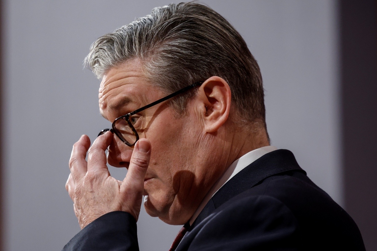 Keir Starmer addressing media on Iran policy with flags and microphones in the background, highlighting diplomatic relations.