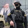 In Tehran, Iran, on Tuesday, a member of the Iranian security forces dressed in all black and holding a large firearm stands guard in front of a large banner displaying an image of Iran's former longtime supreme leader, Ayatollah Ali Khamenei.