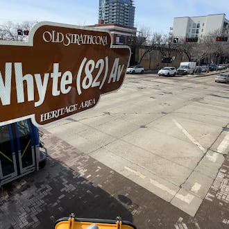 Whyte Avenue sign hovers over the crosswalk at 104th Street on a winter day.