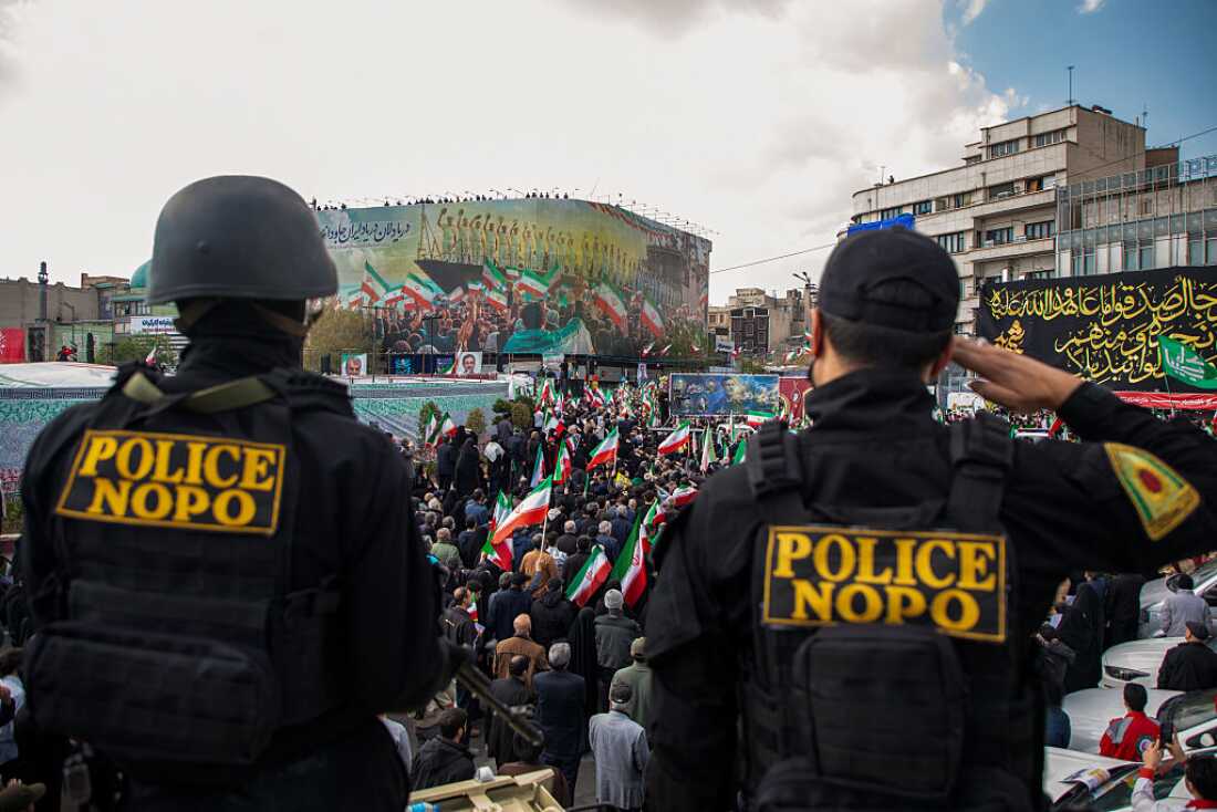 Members of security forces watch over the crowd during a funeral procession held for IRGC Navy Chief Alireza Tangsiri, alongside other senior naval commanders and their families who were killed in US-Israeli strikes in late March, on April 1, 2026 in Tehran, Iran.