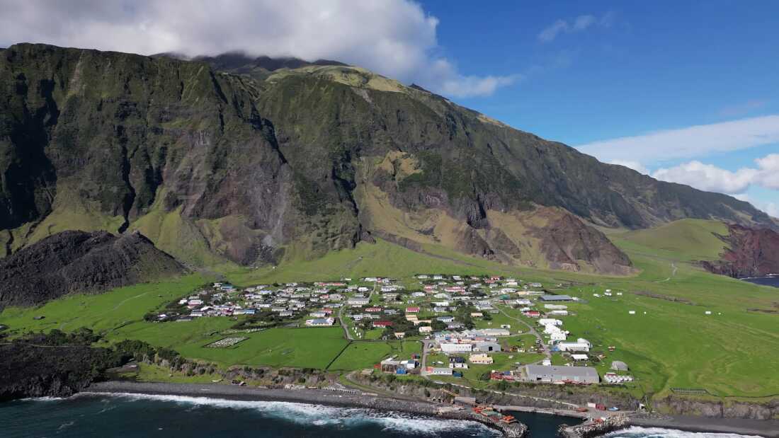 Aerial photo of a small island town nestled at the foot of mountains.