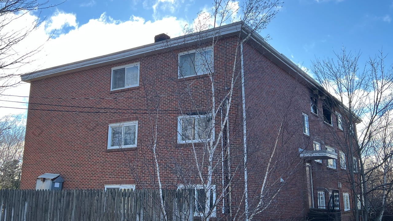 A photo of an apartment building shows a unit with some windows missing, as a result of the fire at the premises.
