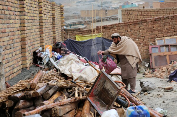Neighbor Mohibullah Niazi searches through items piled up at a house damaged by an earthquake in the village of Ittefaq, on the outskirts of Kabul, Afghanistan, Saturday, April 4, 2026. (AP Photo/Siddiqullah Alizai)