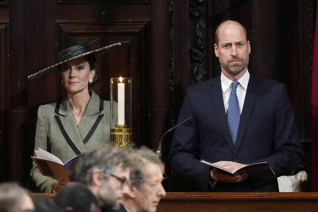 Two people holding orders of service sit in wooden pews in a cathedral.
