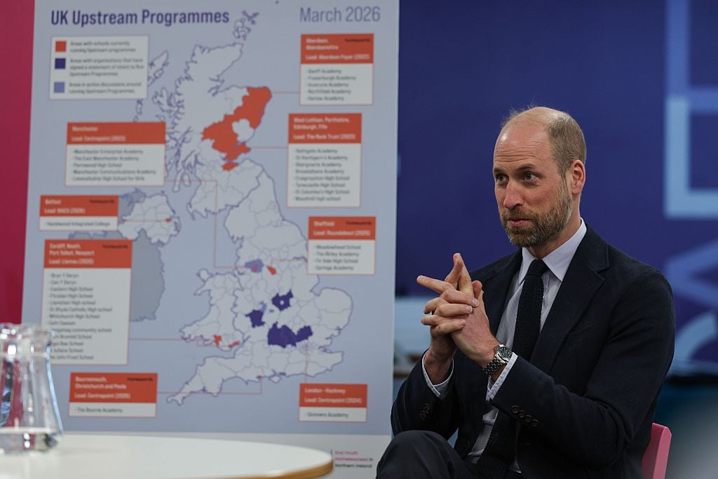 A person sits beside a large poster with a map of the United Kingdom and the words "UK Upstream Programmes" in large letters.