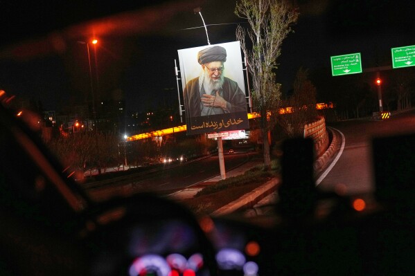 A picture of the late Iranian Supreme Leader Ayatollah Ali Khamenei hangs on the side of the road in the outskirts of Tehran, Iran, early Sunday, April 5, 2026. (AP Photo/Francisco Seco)