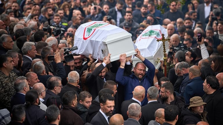 Men carry the coffins with the bodies of Pierre Mouawad,...