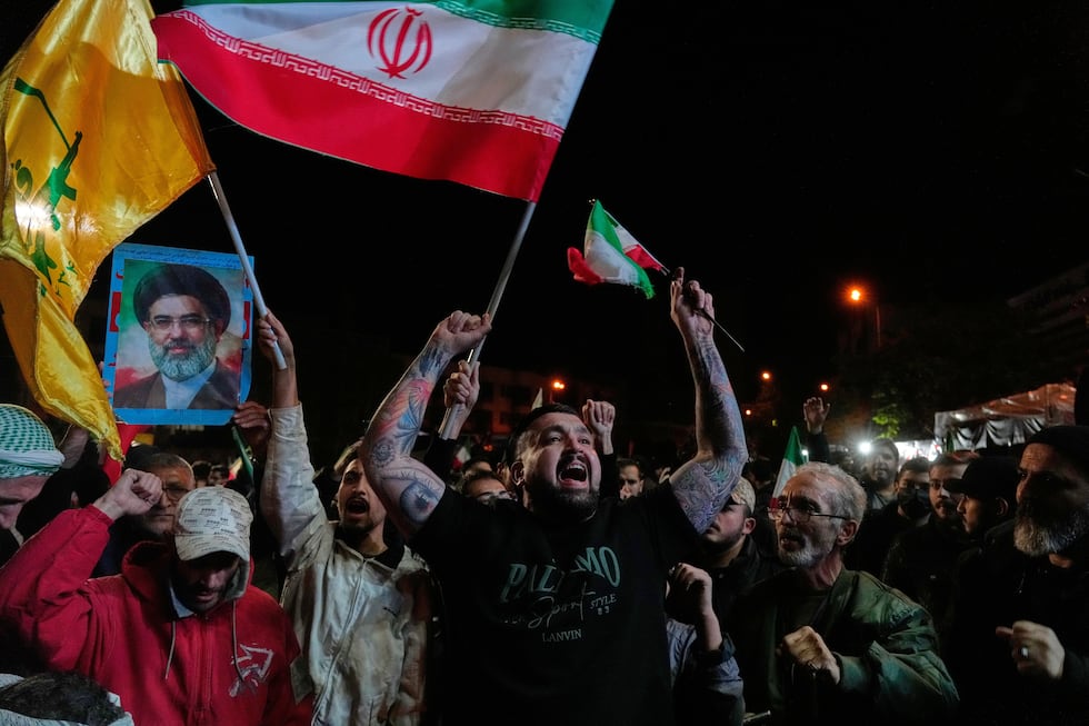 Pro-government demonstrators chant slogans as they hold Iranian flags and a poster of the...