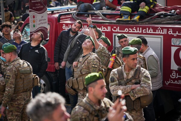 Lebanese army soldiers and first responders look up at an Israeli drone flying overhead at the site of an Israeli airstrike in Beirut, Lebanon, Wednesday, April 8, 2026. (AP Photo/Emilio Morenatti)