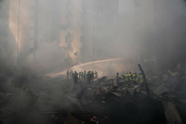 Firefighters, volunteers and first responders walk on smoldering debris at the site of an Israeli airstrike that struck a building in Beirut, Lebanon, Wednesday, April 8, 2026. (AP Photo/Hassan Ammar)