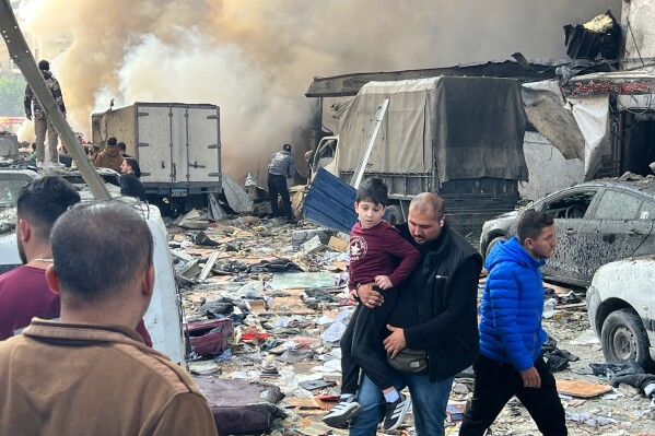 A man holds a child as they leave the site of an Israeli airstrike that struck an apartment building in Beirut, Lebanon, Wednesday, April 8, 2026. (AP Photo/Hussein Malla)