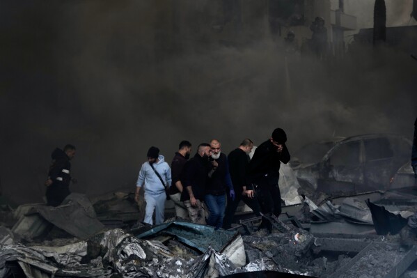 First responders and volunteers emerge through the smoke at the site of an Israeli airstrike that struck an apartment building in Beirut, Lebanon, Wednesday, April 8, 2026. (AP Photo/Bilal Hussein)