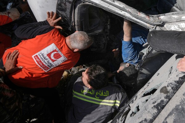 First responders try to rescue a man trapped in a car at the site of an Israeli airstrike in Beirut, Lebanon, Wednesday, April 8, 2026. (AP Photo/Bilal Hussein)