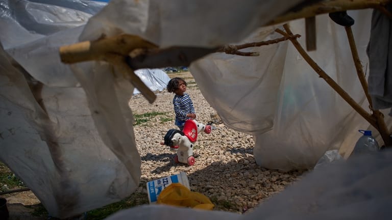 Ali, 4, holds a toy horse next to the tent...
