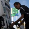 Carlos Ferre holds a gas pump nozzle as he stands near a gas pump at a gas station in Miami on April 6. Behind him is a tall sign that says regular gasoline is $4.29 and diesel is $5.89.
