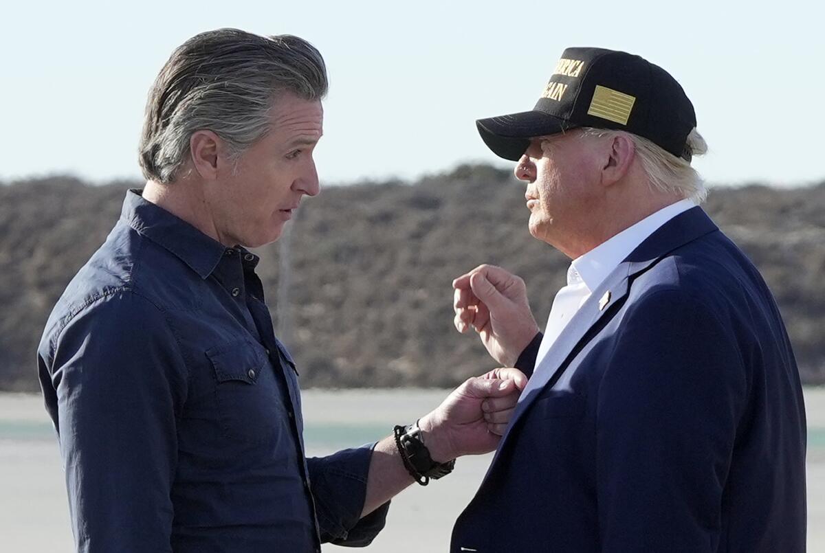 A man in a dark shirt, left, gestures toward the chest of another man, in dark suit and ballcap, while speaking