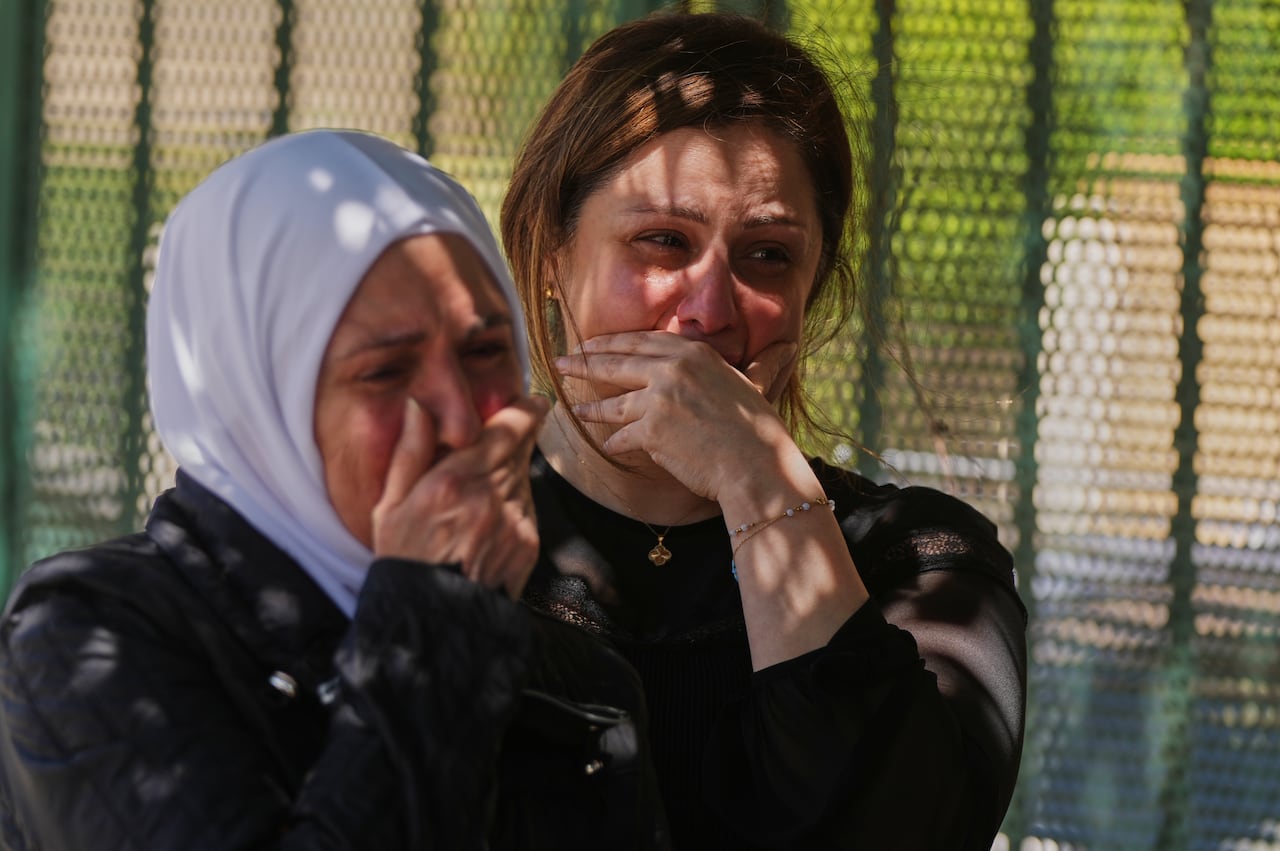 Two crying women stand side by side