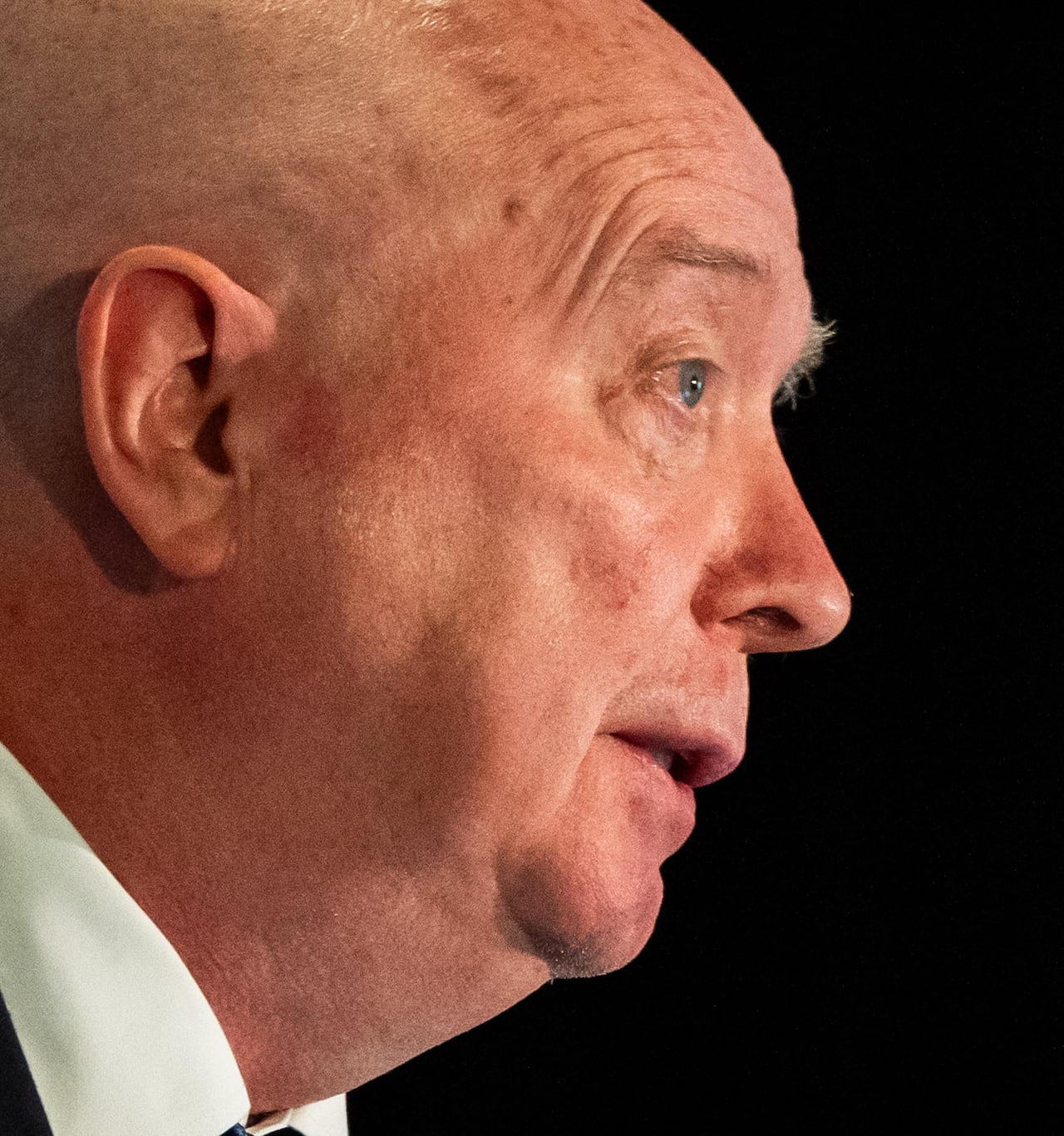 A bald man is seen in profile.