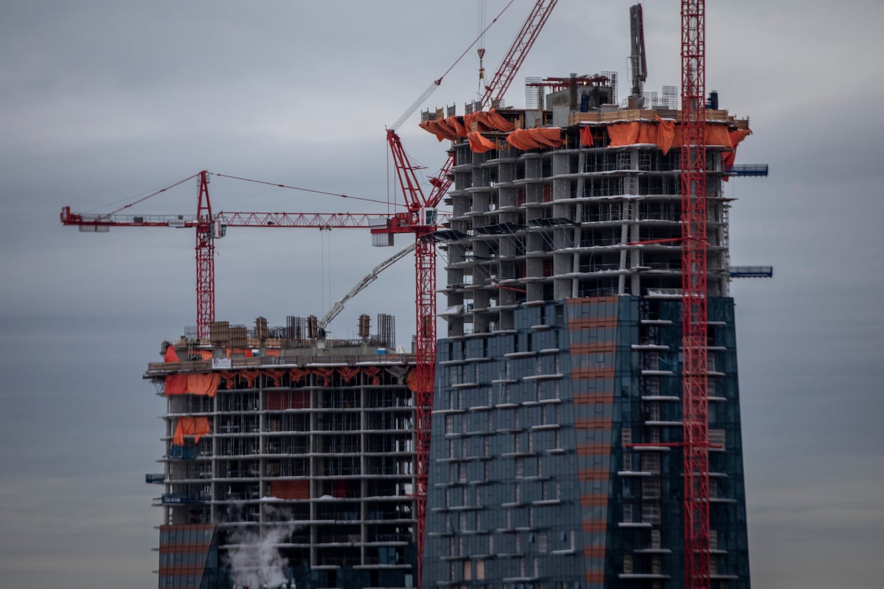 Two towers are under construction under a cloudy sky