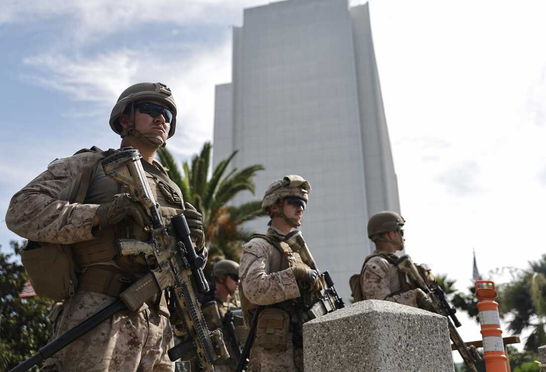 Three Marines holding large firearms stand guard at an entrance to the Wilshire Federal Building in Los Angeles on June 13, 2025.