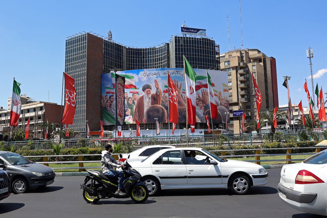 Vehicles in Tehran drive past a billboard featuring an image of Iran's slain supreme leader Ayatollah Ali Khamenei