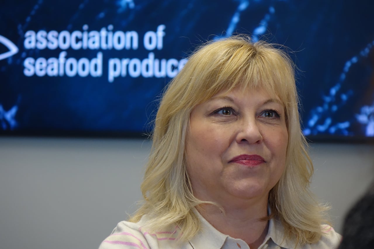 A smiling woman with blonde hair stands in a board room.