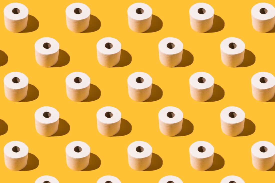 Pattern of white toilet paper rolls on yellow background. Concept of going to the bathroom, cleaning and pooping and peeing.