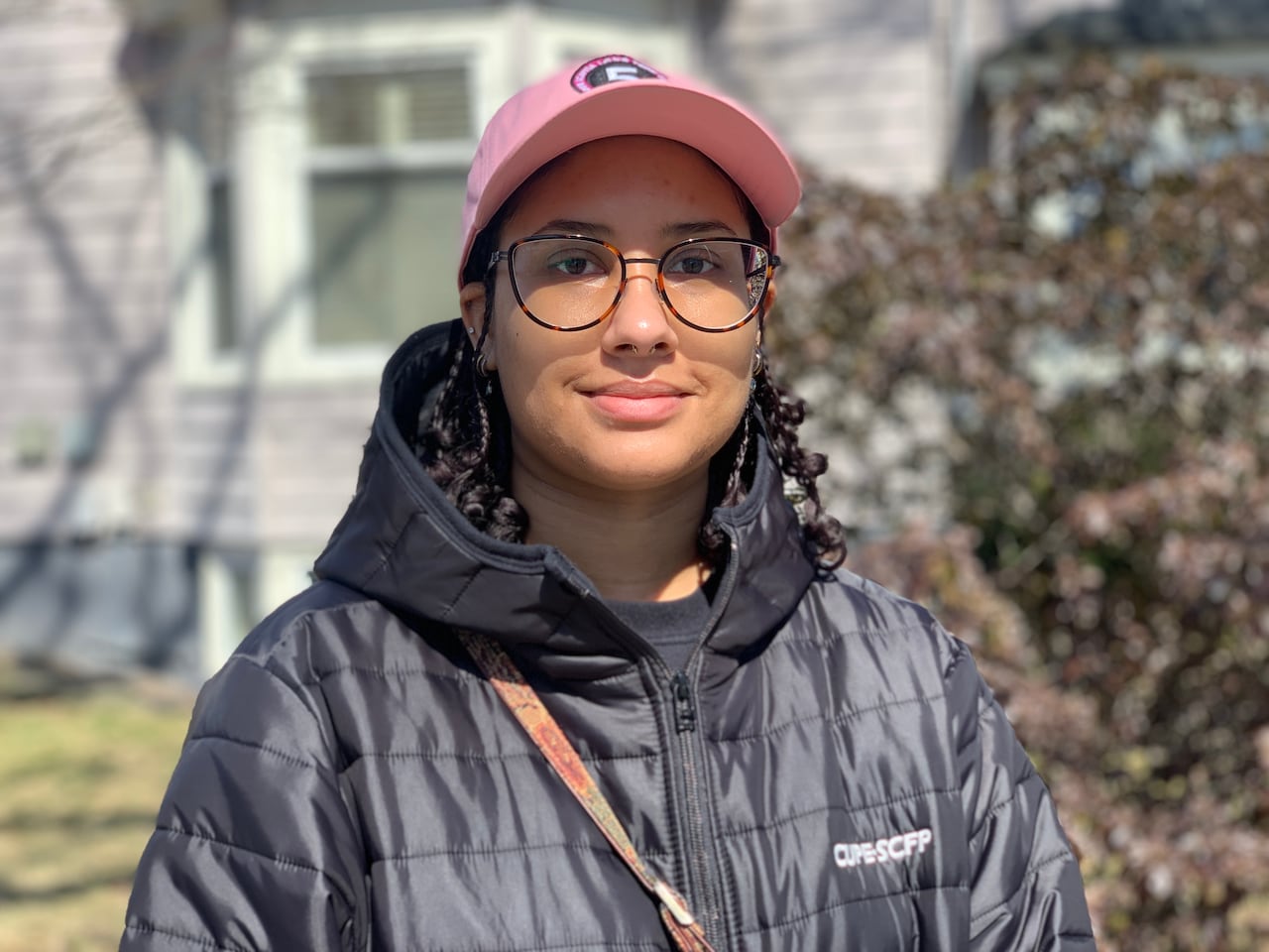A portrait of a woman wearing a pink ball cap.