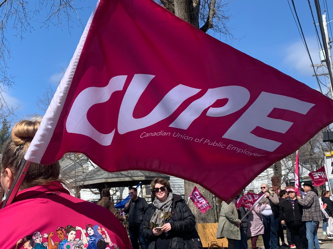 A person holds a flag for CUPE, the Canadian Union of Public Employees, at a rally.
