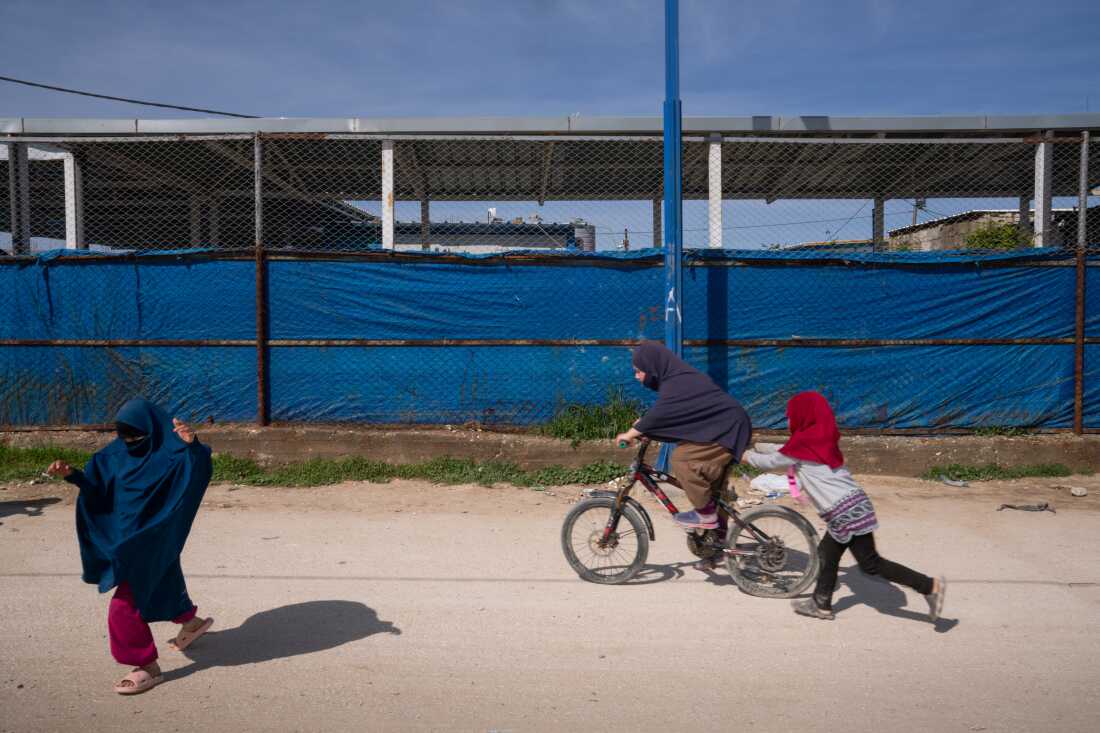 Children ride a bicycle and play in the Roj camp in Northeast Syria in March.