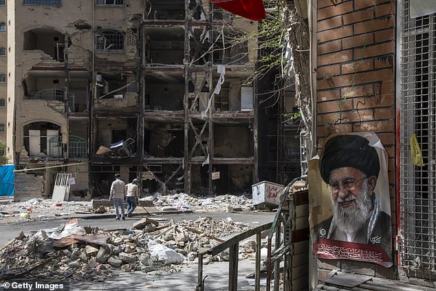 TEHRAN, IRAN - APRIL 14: Men walk past a damaged residential building that, according to Iranian authorities, was hit by a strike on March 4 during the U.S.-Israeli military campaign on April 14, 2026 in southeastern Tehran, Iran. On April 8 President Donald Trump announced a two-week ceasefire between the US and Iran, conditional on shipping being allowed to resume through the Strait of Hormuz. Peace talks held in Pakistan have since stalled, reportedly over Iran's nuclear stockpile and continued blockade of the Strait of Hormuz. (Photo by Majid Saeedi/Getty Images)
