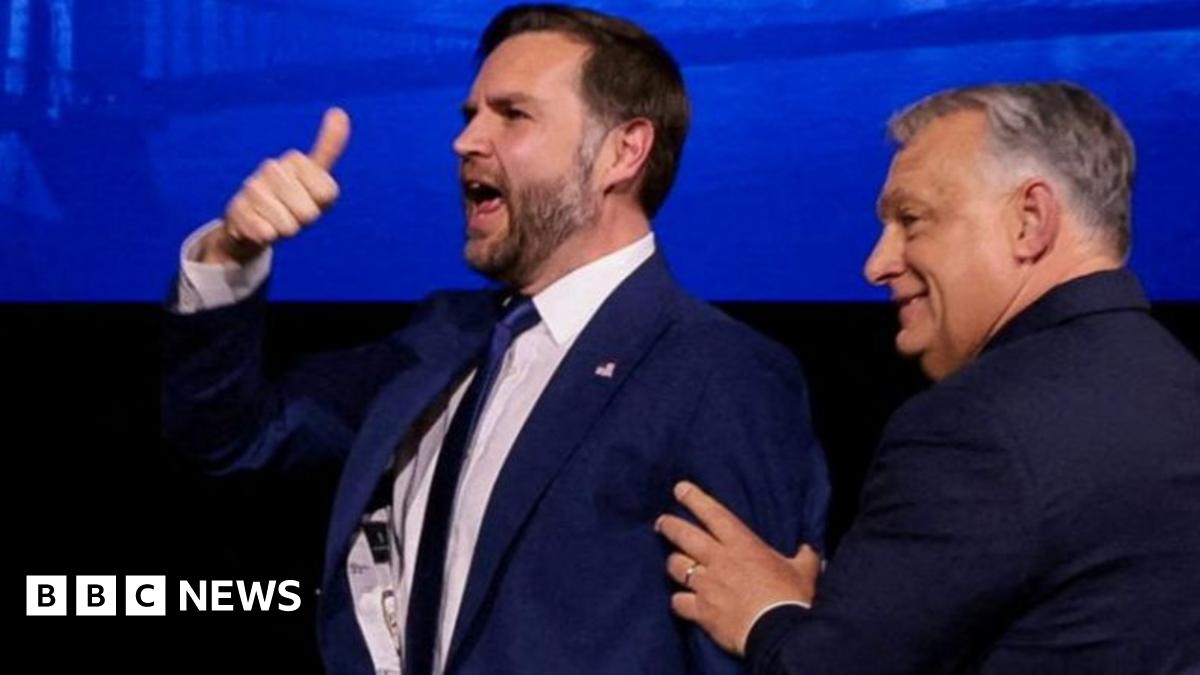 A man holds his thumb in the air while another man pushes him in the back from the right