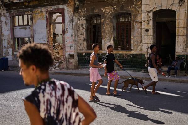 People walk a dog on a street in Havana, Wednesday, March 25, 2026. (AP Photo/Ramon Espinosa)