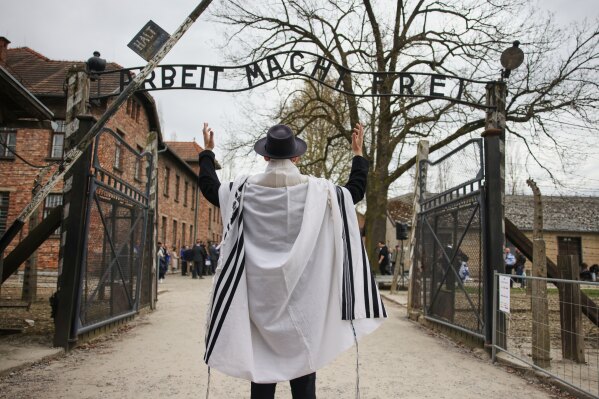 A man stands in front of the Auschwitz entrance prior to the annual "March of the Living" to commemorate the Holocaust, a yearly Holocaust remembrance march between the former death camps of Auschwitz and Birkenau, in Oswiecim, Poland, on Tuesday, April 14, 2026. (AP Photo/Beata Zawrzel)