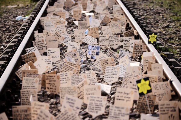 Signs are put between the rails during the annual "March of the Living" to commemorate the Holocaust, a yearly Holocaust remembrance march between the former death camps of Auschwitz and Birkenau, in Oswiecim, Poland, on Tuesday, April 14, 2026. (AP Photo/Beata Zawrzel)