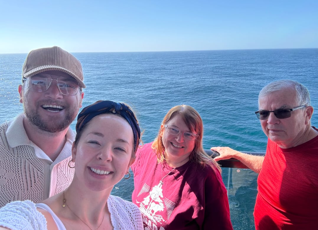 Four people smile with a body of water behind them