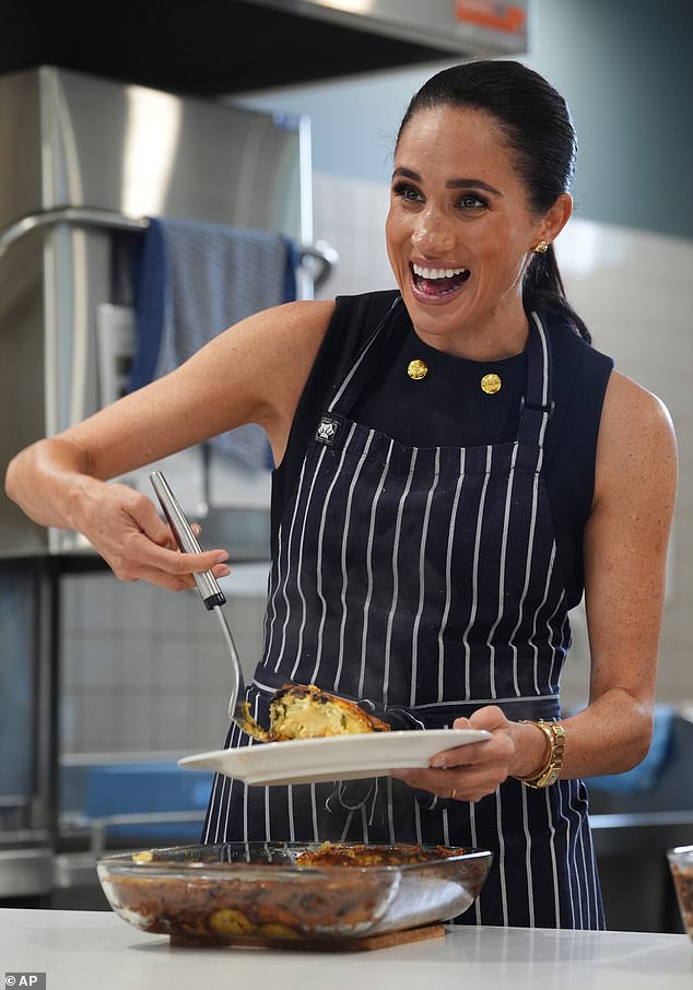 Meghan Markle, the Duchess of Sussex, serves lunch to a resident during a visit to McAuley Community Services for Women, a women's homeless and family violence shelter in Footscray, a suburb of Melbourne, Australia Tuesday, April 14, 2026. (Jonathan Brady/Pool Photo via AP)