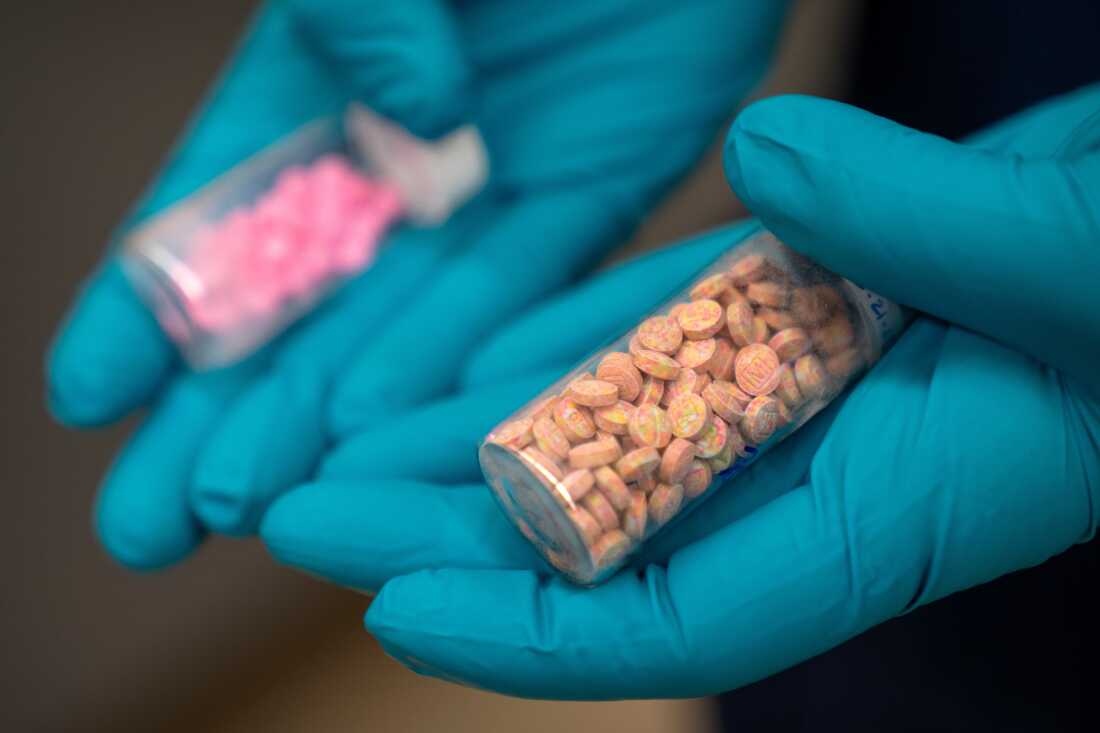 A forensic chemist with the Drug Enforcement Administration holds vials of fentanyl pills at a DEA research laboratory in this file photo. Fentanyl deaths are plunging in the U.S, but the recovery is threatened by a new "synthetic soup" of toxic street drugs.
