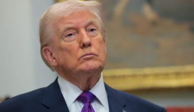 Donald Trump speaking at a press conference podium with an American flag backdrop, emphasizing political discourse