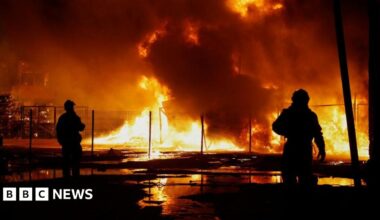 Two rescuers are silhouetted against a backdrop of fire in Kyiv