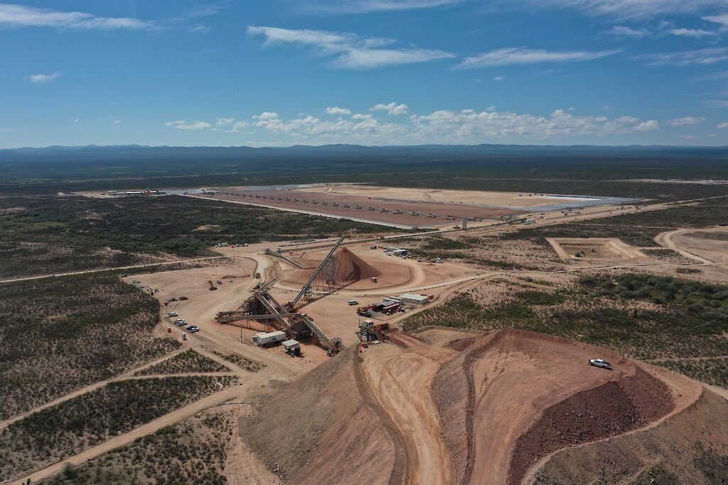 Areal photo of a mine site with buildings and vehicles scattered across the foreground.