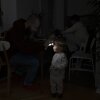 Local resident Stas helps his two-year-old daughter use a headlight