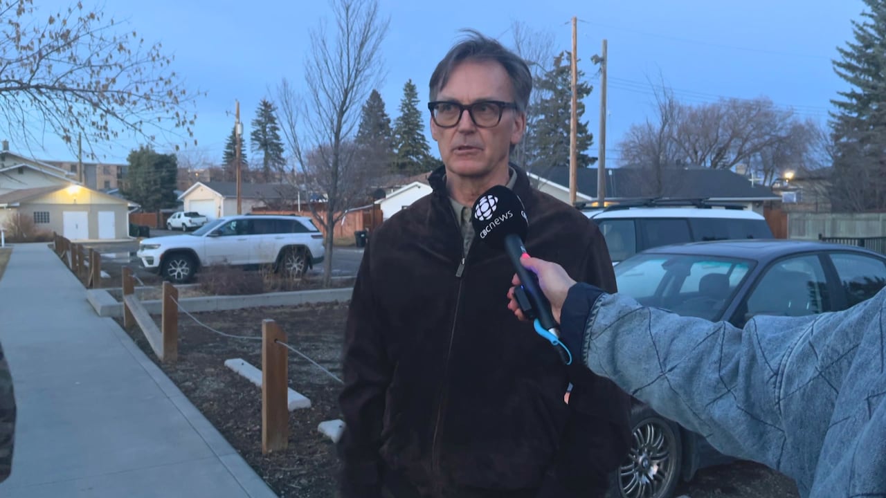 tall man in glasses talking to a microphone