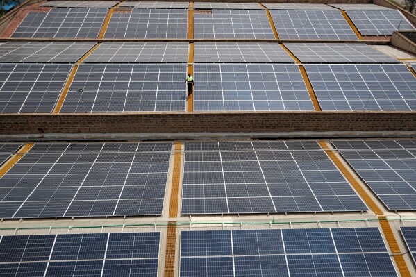 Mark Munyua, CP solar's technician, examines solar panels on the roof of a company in Nairobi, Kenya, Sept. 1, 2023. (AP Photo/Brian Inganga, File)
