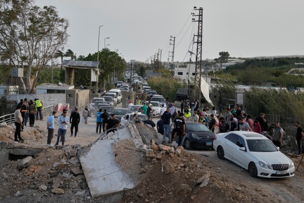 Displaced people returning to their villages following a ceasefire between Hezbollah and Israel, cross the destroyed Qasmiyeh bridge near Tyre city, south Lebanon, Friday, April 17, 2026. (AP Photo/Mohammed Zaatari)