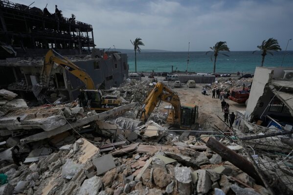 Rescuers search for victims in the rubble of a destroyed building that was struck in Israeli airstrikes in the city of Tyre, south Lebanon, Friday, April 17, 2026. (AP Photo/Mohammed Zaatari)