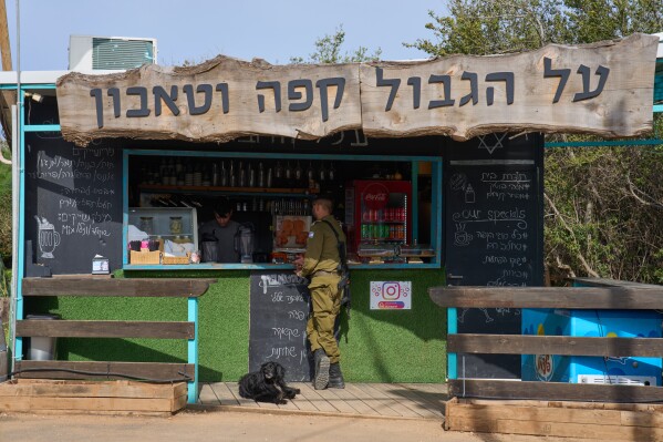 An Israeli soldier orders drinks from a coffee shop in northern Israel, on the border with Lebanon following a ceasefire between Israel and Hezbollah, Friday, April 17, 2026. Signage in Hebrew reads, "Coffee on the border."(AP Photo/Ariel Schalit)