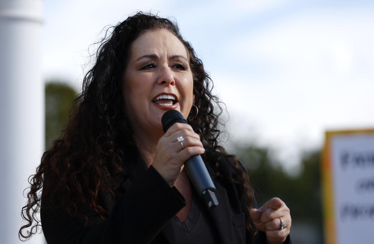 A woman holds and speaks into a microphone.