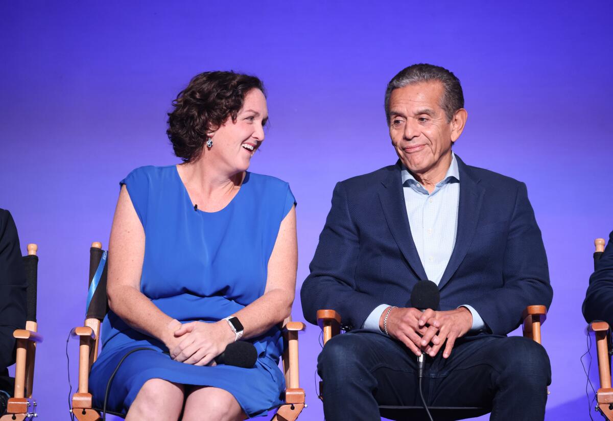 A seated woman links toward a man seated next to her.